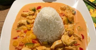 Paprika-Zucchini-Sahne Hähnchen mit Reis auf einem Teller serviert