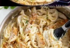 Pasta mit Hähnchenbrust in Käsesauce auf einem Teller serviert.