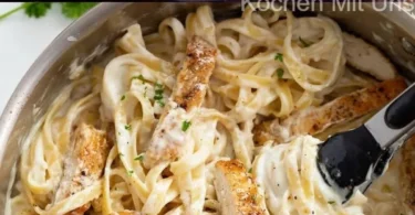 Pasta mit Hähnchenbrust in Käsesauce auf einem Teller serviert.