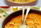 Pilz-Spaghetti mit Parmesan auf einem Teller, garniert mit frischen Kräutern.