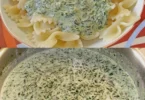 Schüssel mit Spinat-Cremekäse-Sauce auf einem Holzbrett
