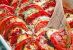 Tomaten-Zucchini-Gratin mit Mozzarella auf einem Teller serviert