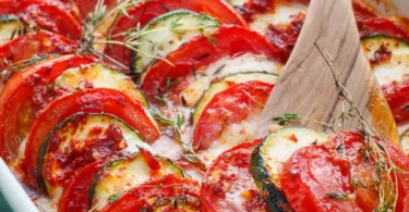 Tomaten-Zucchini-Gratin mit Mozzarella auf einem Teller serviert