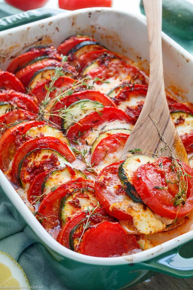 Tomaten-Zucchini-Gratin mit Mozzarella auf einem Teller serviert