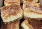 Zimtkäsekuchen mit Zimtstaub auf einem Teller, dekoriert mit frischem Obst