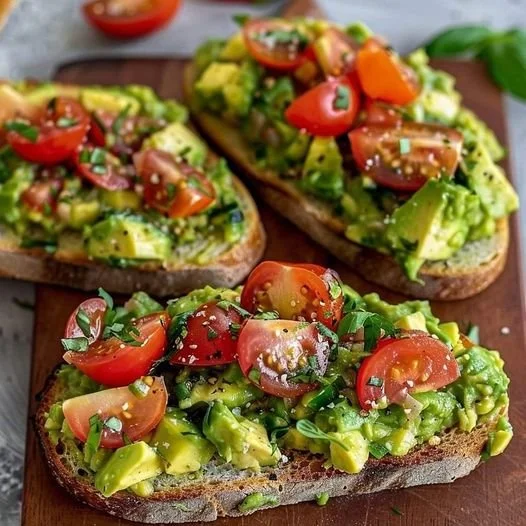 Leckeres Avocadobrot mit frischen Tomaten auf einem Holzbrett