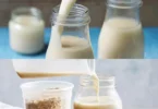 Glas Haferwasser auf einem Holztisch mit Haferflocken und einem Genussbuch