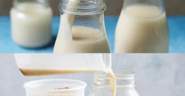 Glas Haferwasser auf einem Holztisch mit Haferflocken und einem Genussbuch