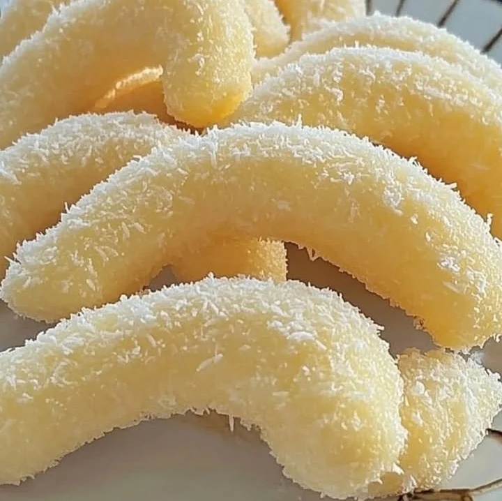 Leckere Kokos-Sahnekipferl auf einem Teller, perfekt zum Naschen.
