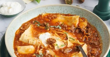 Eine Schüssel Lasagnesuppe, garniert mit Käse und frischen Kräutern.
