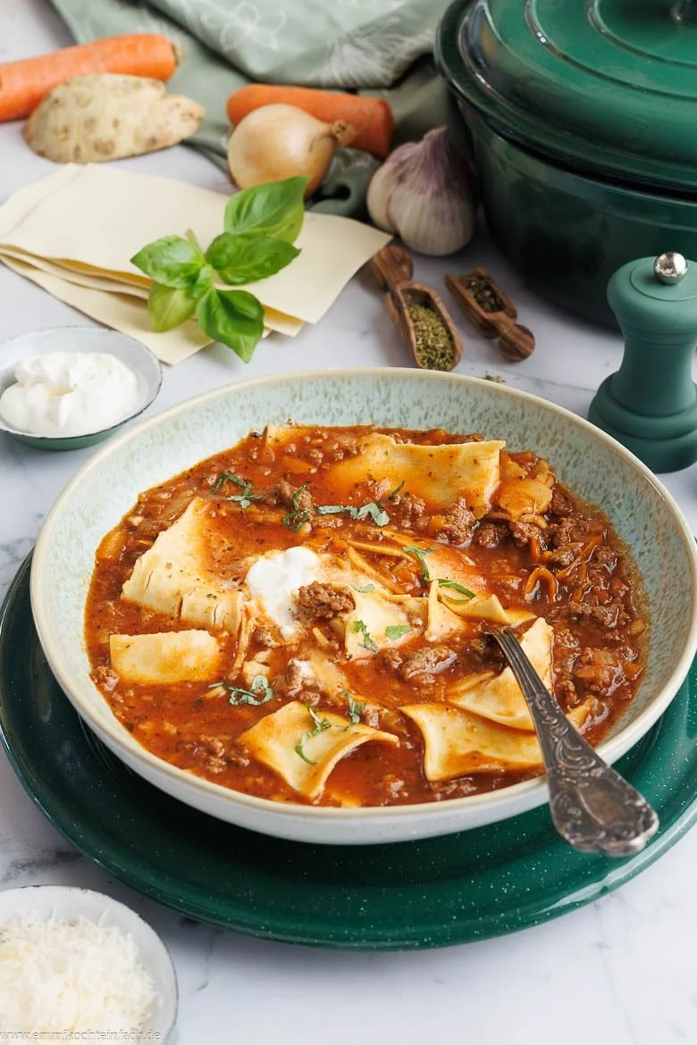 Eine Schüssel Lasagnesuppe, garniert mit Käse und frischen Kräutern.
