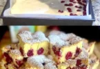 Ein Stück Quark Kirschkuchen auf einem Teller mit frischen Kirschen daneben.