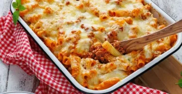 Leckere Portion Rigatoni al forno, frisch aus dem Ofen, serviert mit Käse und Kräutern.