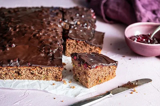 Saftiger Zucchini-Kuchen auf einem Teller, dekoriert mit frischen Kräutern.