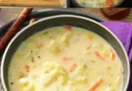 Cremige Blumenkohlsuppe mit frischen Zutaten im weißen Teller serviert.