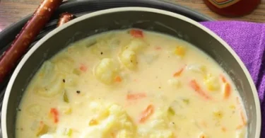 Cremige Blumenkohlsuppe mit frischen Zutaten im weißen Teller serviert.