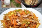 Chinesisch gebratene Nudeln mit Hühnchen, Gemüse und Ei auf einem Teller serviert