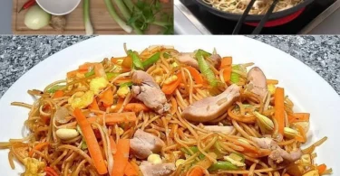 Chinesisch gebratene Nudeln mit Hühnchen, Gemüse und Ei auf einem Teller serviert